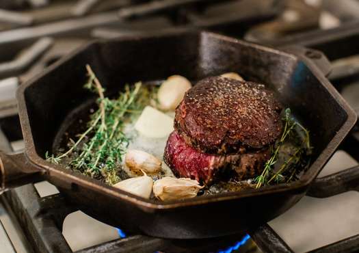 filet mignon in cast iron skillet with herbs